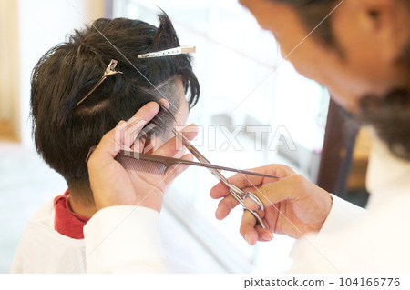 Hair stylist's hand cutting men's hair 104166776