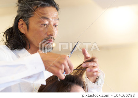 Experienced male hairdresser cutting customer's hair Experienced male hairdresser cutting customer's hair 104166788