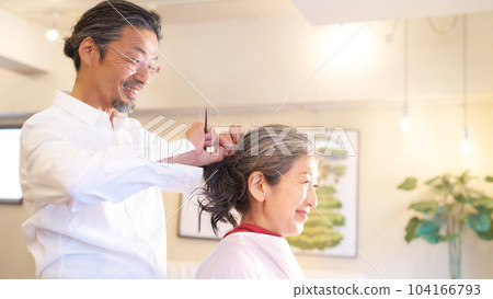 Hair stylist and female customer during treatment at hair salon 104166793