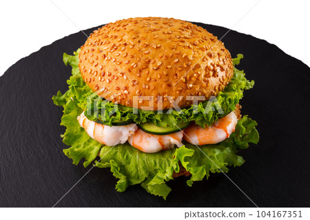 Burger with sesame bun, shrimps, fresh green salad and cucumbers. Burger with sesame bun, shrimps, fresh green salad and cucumbers. 104167351