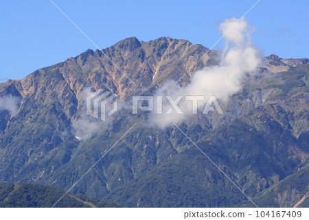 Goryudake in the Northern Alps from Azumino in the midsummer of Shinshu surrounded by deep green Goryudake in the Northern Alps from Azumino in the midsummer of Shinshu surrounded by deep green 104167409
