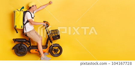 Shocked confident delivery man in cap riding bicycle with raised clenched fist, wearing thermo backpack bag isolated over yellow background. Mockup, advertisement area. Shocked confident delivery man in cap riding bicycle with raised clenched fist, wearing thermo backpack bag isolated over yellow background. Mockup, advertisement area. 104167728