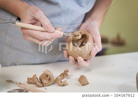 woman forming clay pot shape by hands, closeup in artistic studio 104167912