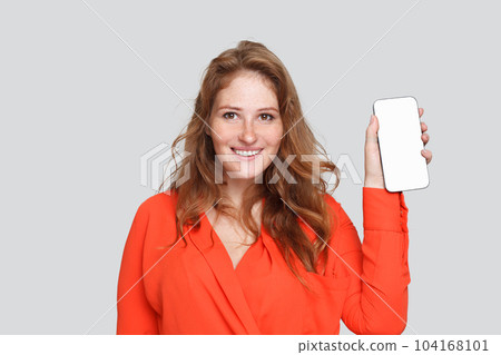 Happy smiling woman showing smartphone with empty white display for app on white studio background 104168101