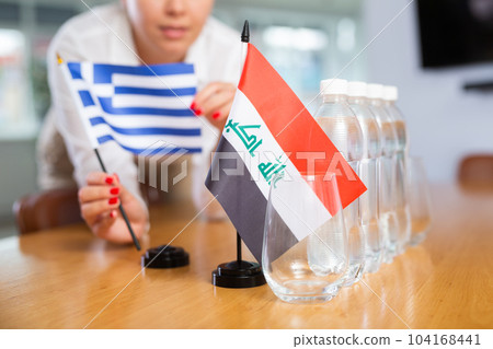Unrecognizable girl sets midget flags of Iraq and Greece before international negotiations 104168441