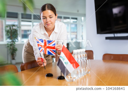 Young lady sets miniatures flags of Iraq and Great Britain for international negotiations 104168641
