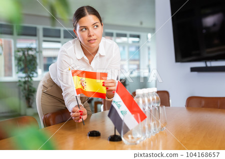 Young lady sets miniatures flags of Iraq and Spain for international negotiations Young lady sets miniatures flags of Iraq and Spain for international negotiations 104168657