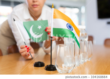 Employee of delegation prepares negotiating table - sets up flag of India and Pakistan Employee of delegation prepares negotiating table - sets up flag of India and Pakistan 104168664