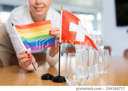 Little flag of Switzerland on table and LGBT flag put next to it by young woman 104168757