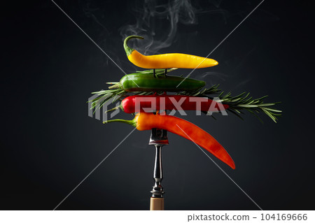 Hot chili peppers with rosemary on black background. 104169666