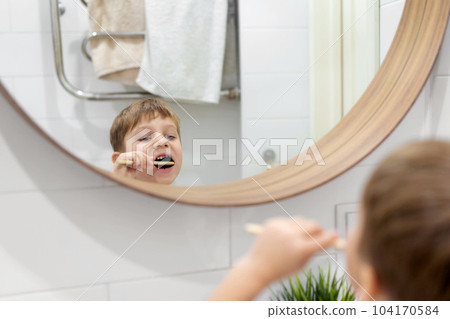 cute 5 years old boy brushing teeth with bamboo tooth brush in bathroom. Image with selective focus 104170584
