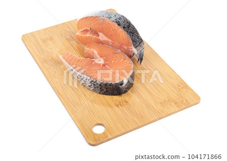 Fresh raw portioned salmon steaks on a cutting board over white background. 104171866