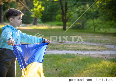 Pray for Ukraine. boy with Ukrainian flag running the summer park. Little kid waving national flag praying for peace. Happy child celebrating Independence Day 104171900
