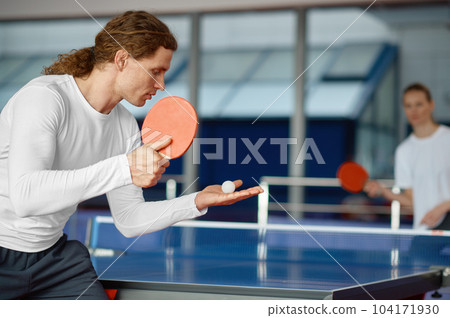 Man and woman playing table tennis, focus on sportsman player serving Man and woman playing table tennis, focus on sportsman player serving 104171930