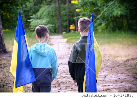 flags of Ukraine in hands of two boys. Children hold Ukrainian f 104171953