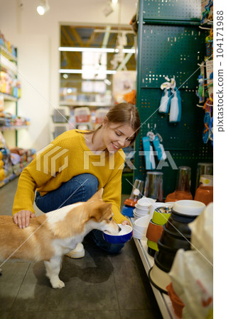 Young woman offering her lovely dog to choose new feed bowl Young woman offering her lovely dog to choose new feed bowl 104171988