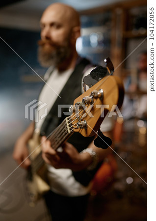Portrait of handsome bearded guitarist of rock band playing guitar 104172056