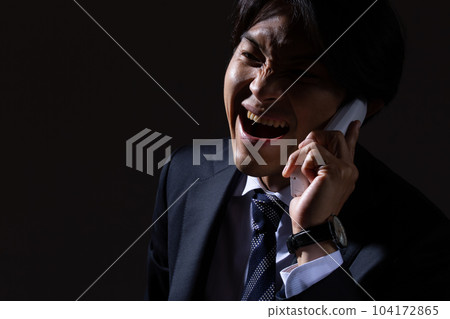 Male businessman making an angry phone call on black background 104172865