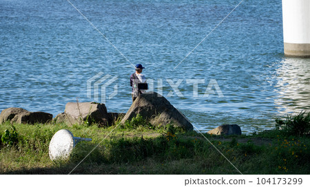 A man fishing along the Tama River 104173299