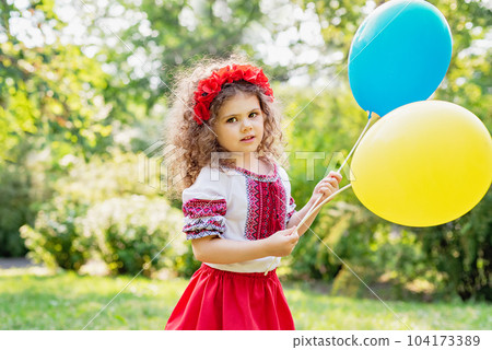 Girl in traditional ukrainian wreath on head blue and yellow flag of Ukraine in field. Ukraine's Independence Flag Day. Constitution day. 24 August. Patriotic holiday. 104173389