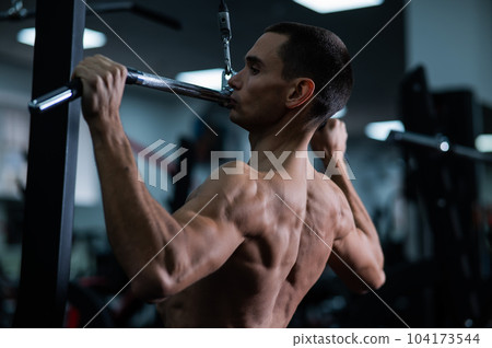 A man does a chest pulldown in the gym. 104173544