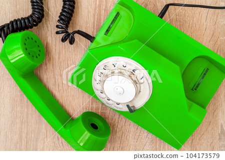 Old green telephone on wooden table, top view 104173579