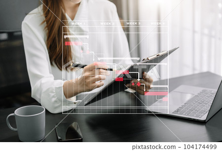 Business woman hand Project manager working and update tasks and Gantt chart scheduling virtual diagram.with smart phone, tablet and laptop in office. 104174499