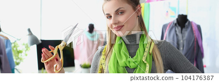 Portrait of a smiling successful fashion designer or tailor holding scissors Portrait of a smiling successful fashion designer or tailor holding scissors 104176387