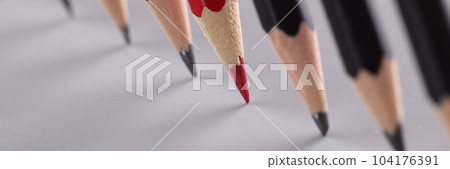 Sharp red pencil stands out from identical black pencils on gray background Sharp red pencil stands out from identical black pencils on gray background 104176391