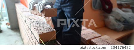 Closeup of industrial bricklayer laying bricks at construction site 104176422