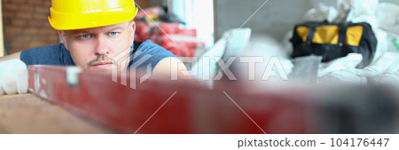 Bricklayer checks evenness of brick wall, brick foundation using spirit level 104176447