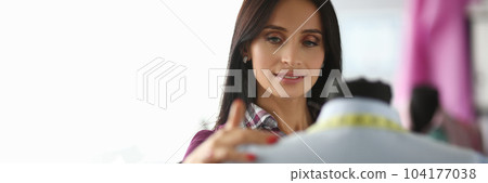 Woman seamstress designer stylist looks at clothes on mannequin 104177038