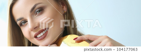 Beautiful blonde smiles and combs long hair Beautiful blonde smiles and combs long hair 104177063