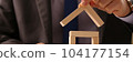 Insurance agent or builder puts up wooden block to showcase house shaped wooden structure 104177154