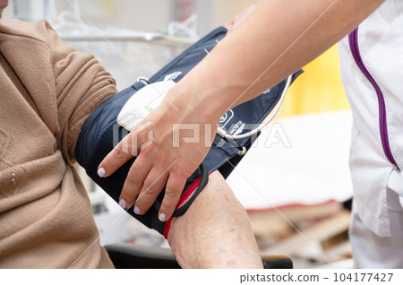 Close up hand of nurse working and adjusting blood pressure gauge on senior woman hand in nursing 104177427