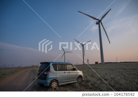Blue car at windmills at sunset. Alternative energy source. Blue car at windmills at sunset. Alternative energy source. 104178592
