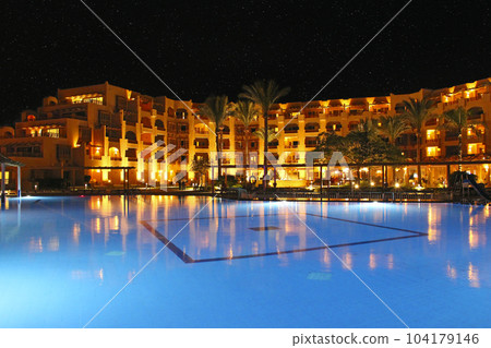 Pool and evening hotel on vacation. People relax by evening near pool Pool and evening hotel on vacation. People relax by evening near pool 104179146