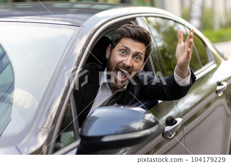 Joyful and happy car driver smiling and looking at camera, mature businessman waving his hand in greeting gesture, boss in business suit driving car. 104179229