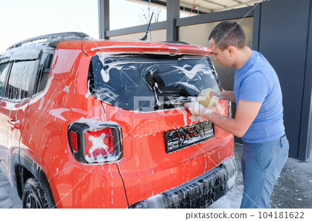A man washing a car with soap, car wash. Car in foam 104181622