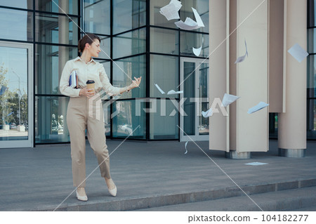 Business woman runs out of an office building throwing paperwork around. How to freeze current affairs before vacation or weekend, time management problems Business woman runs out of an office building throwing paperwork around. How to freeze current affairs before vacation or weekend, time management problems 104182277