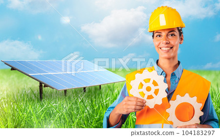 Woman holds two pieces of gears against in front of a solar panel Woman holds two pieces of gears against in front of a solar panel 104183297