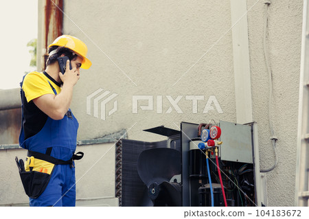 Certified engineer on the phone with client after finishing air conditioner maintenance check up. Licensed electrician calling customer to inform him about electrical issues found in hvac system 104183672