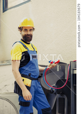 Portrait of smiling experienced technician commissioned for outdoor air conditioner maintenance, holding professional manifold gauges. Engineer using hvac system refrigerant pressure benchmarking tool Portrait of smiling experienced technician commissioned for outdoor air conditioner maintenance, holding professional manifold gauges. Engineer using hvac system refrigerant pressure benchmarking tool 104183679