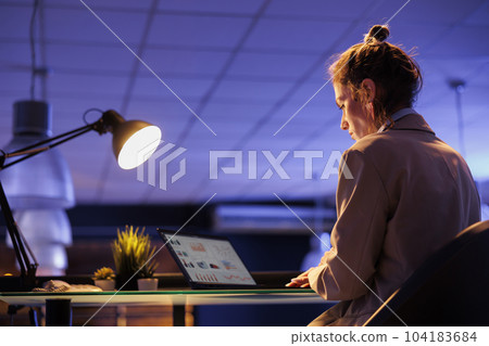 Executive manager sitting at desk table in business office, analyzing company strategy planning investment plan to increase profit. Businesswoman working late at night marketing graphs report 104183684