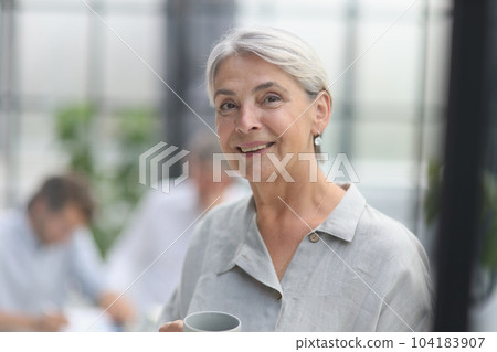 close-up mature woman holding a cup in the office 104183907