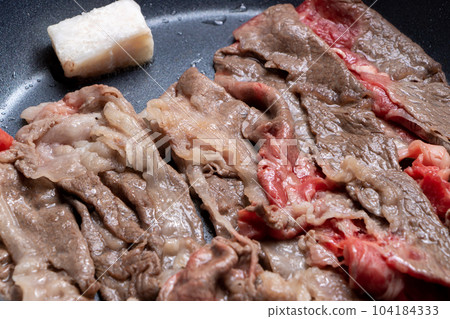A cooking scene where beef (thinly sliced) is baked in a frying pan. 104184333
