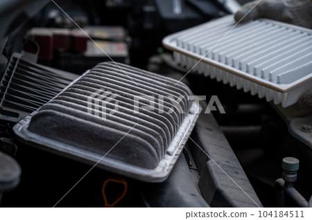The master changes the air filter in the car engine.  104184511