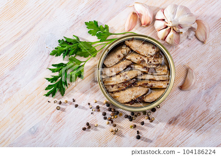 Tinned small smoked sardines on background with greens Tinned small smoked sardines on background with greens 104186224