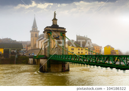 View of Seyssel on Rhone river with Saint-Blaise church and suspension bridge in winter 104186322