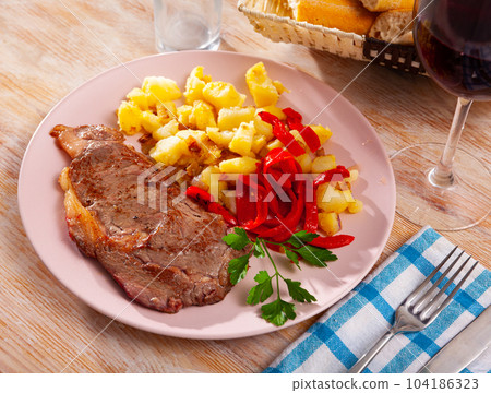Appetizing beef entrecote with french fries and stewed bell peppers at plate 104186323
